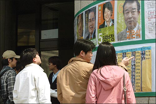 17대 총선 부재자 투표가 시작된 9일 오후 연세대 학생들이 투표소가 설치된 백주년기념관에서 기표를 하기 앞서 선거벽보를 자세히 살펴보고 있다. 